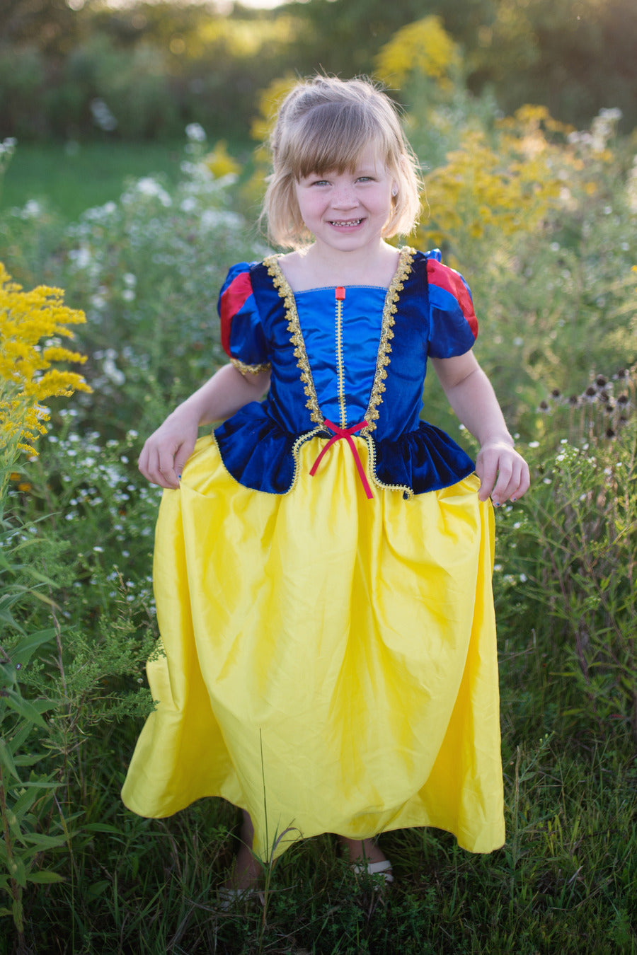 Child in a Snow White costume standing in a field of flowers