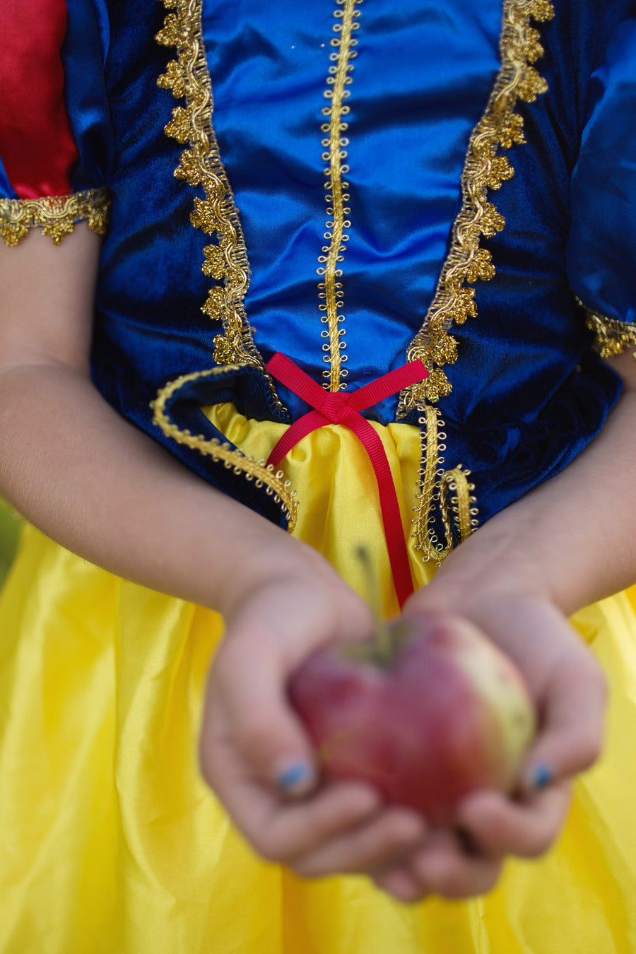 Person in a Snow White costume holding an apple.