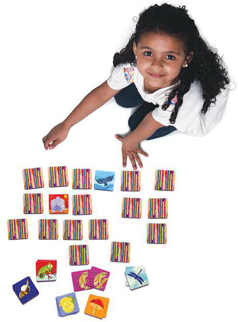 girl looking up and smiling with matching game in front of her