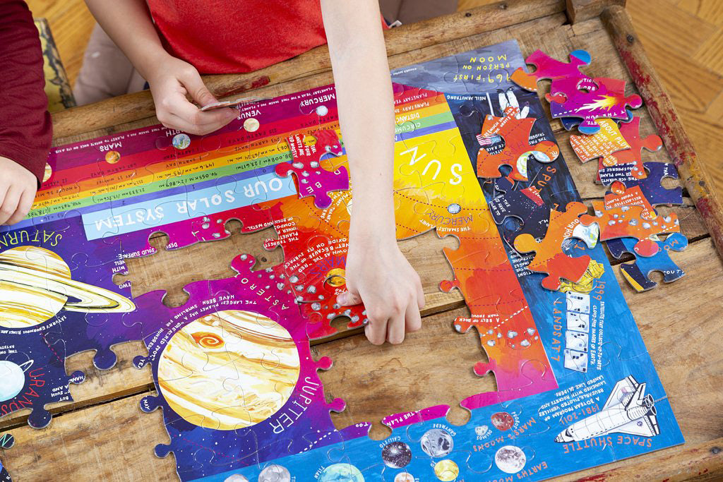 childs hands putting together a solar system puzzle