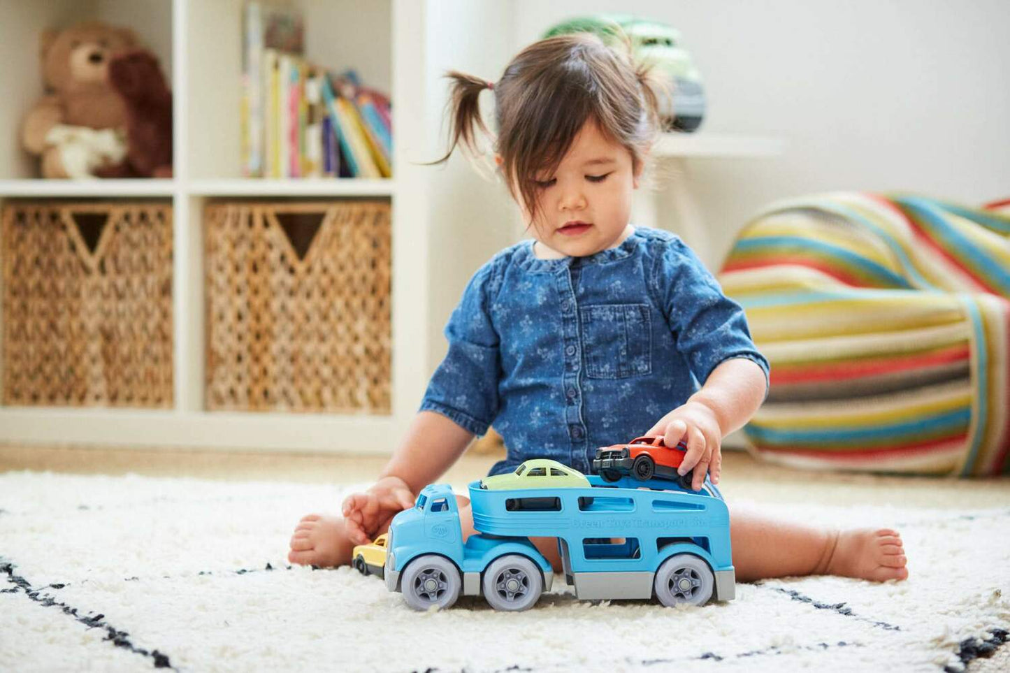 A young toddler with sitting on a rug and playing with the blue truck.