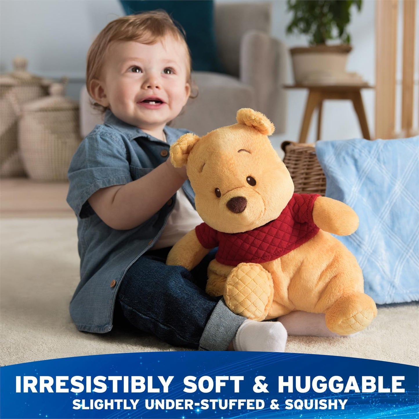 A toddler sitting on the floor smiles happily while hugging Winnie the Pooh plush toy .
Across the bottom, a bold blue banner features that reads "Irresistibly Soft & Huggable" above the subtitle "Slightly Under-Stuffed & Squishy".