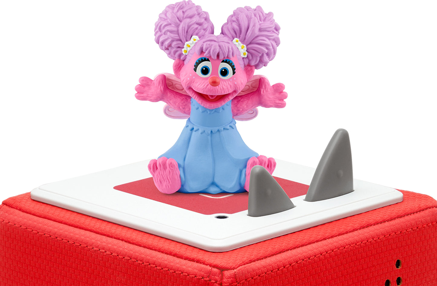 Abby Cadabby figurine with pink hair and blue outfit, sitting with arms open, on a red toniebox