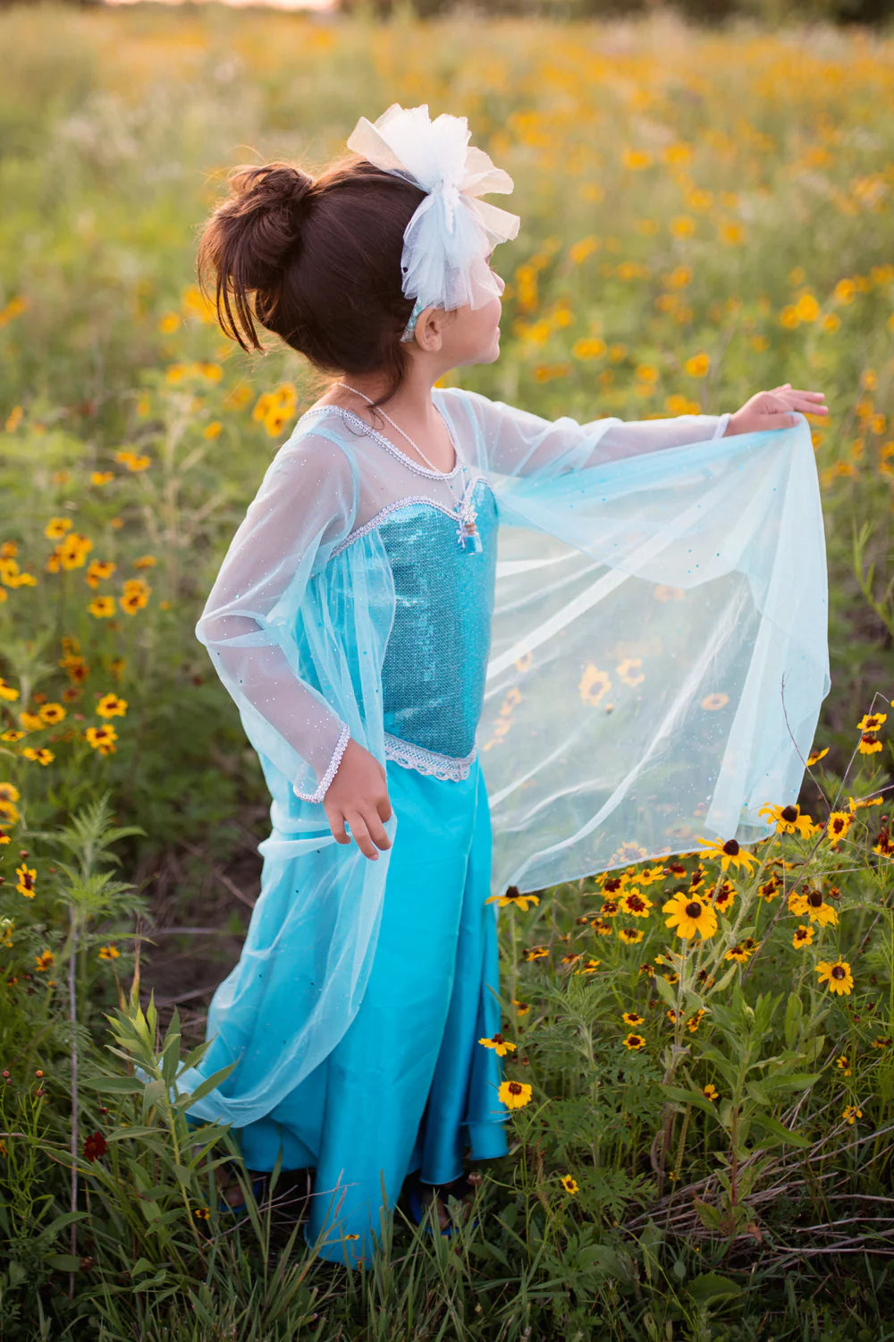 Child in a blue dress standing in a field of yellow flowers