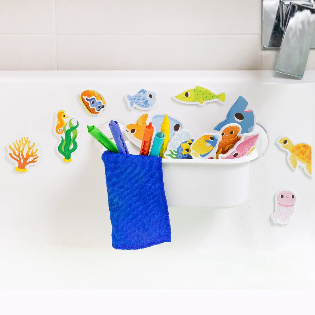Colorful bath toys including fish and sea creatures on a white surface with a blue cup.