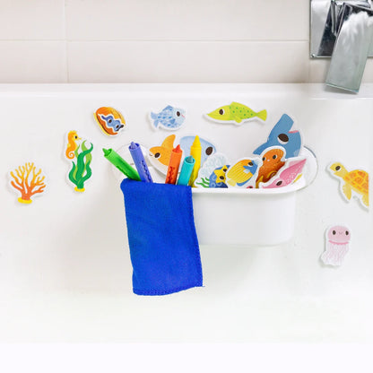 Colorful bath toys including fish and sea creatures on a white surface with a blue cup.
