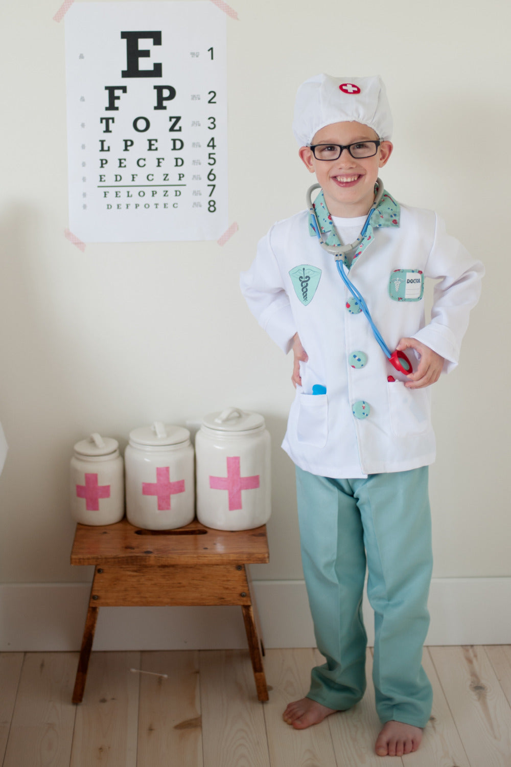 child wearing doctor costume standing by vision test poster