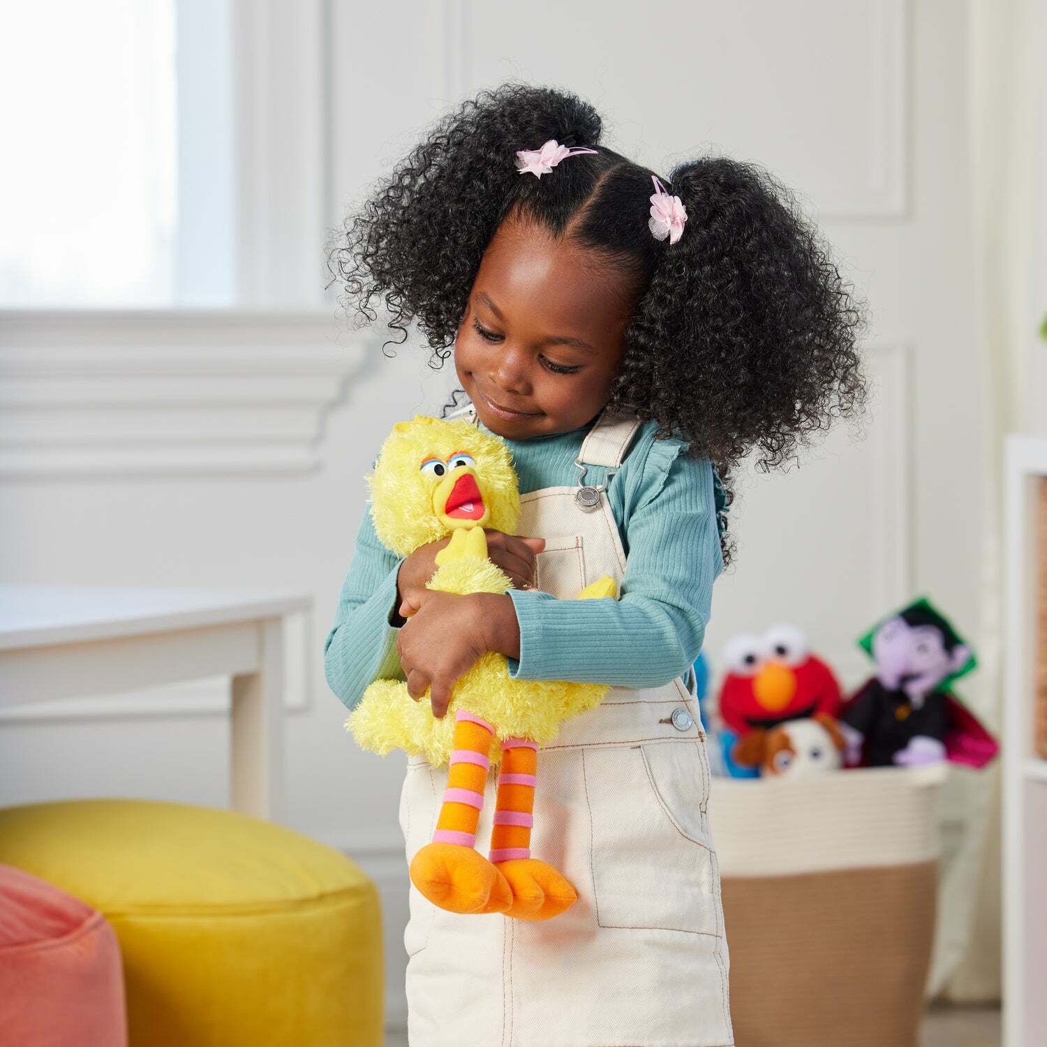 Child holding a yellow plush toy in a room with colorful furniture