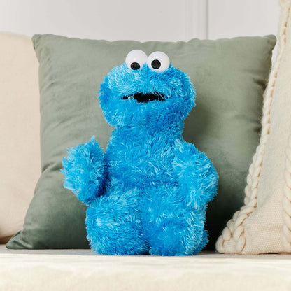 Blue plush toy resembling a character with a surprised expression on a couch.