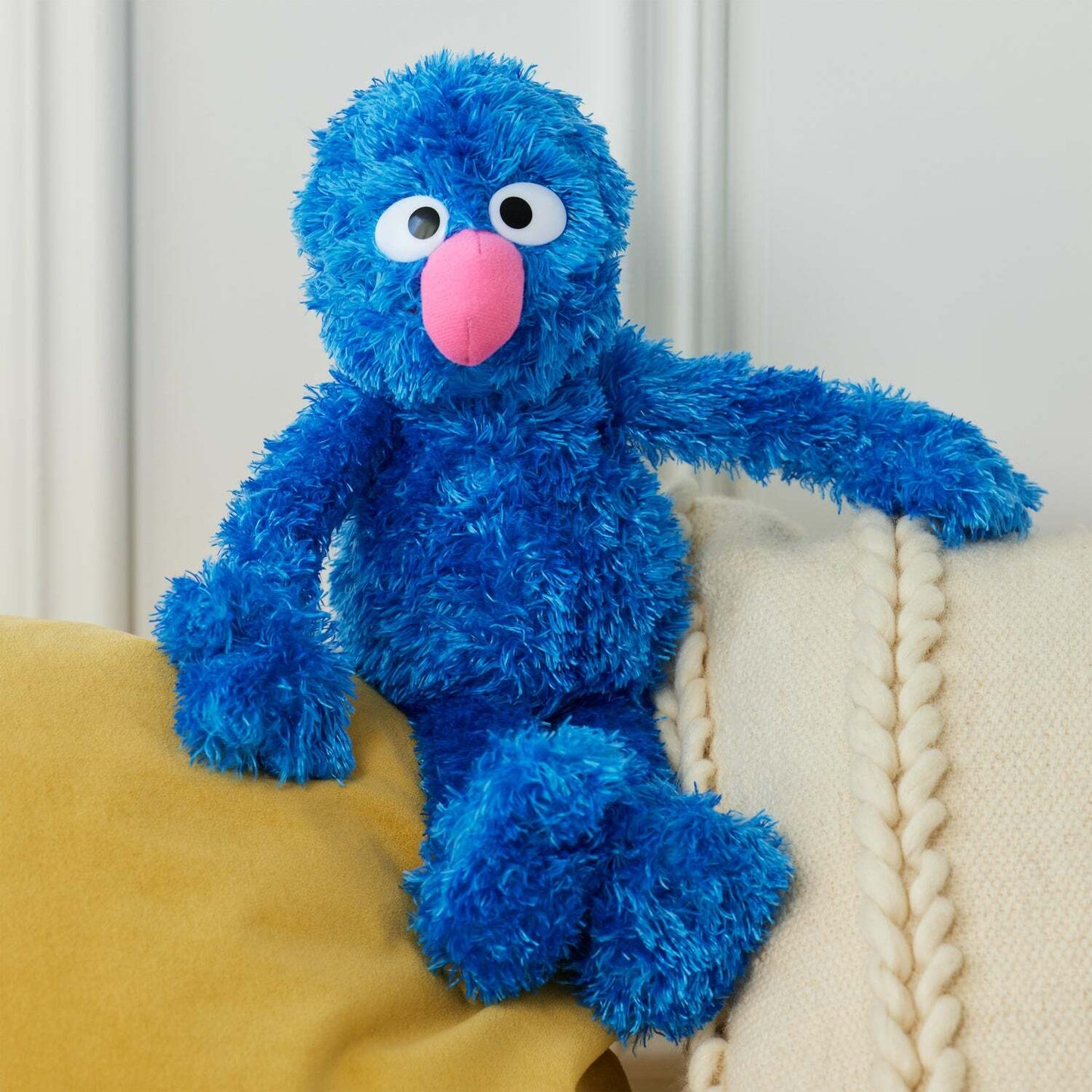 Blue plush toy with a pink nose sitting on a yellow surface