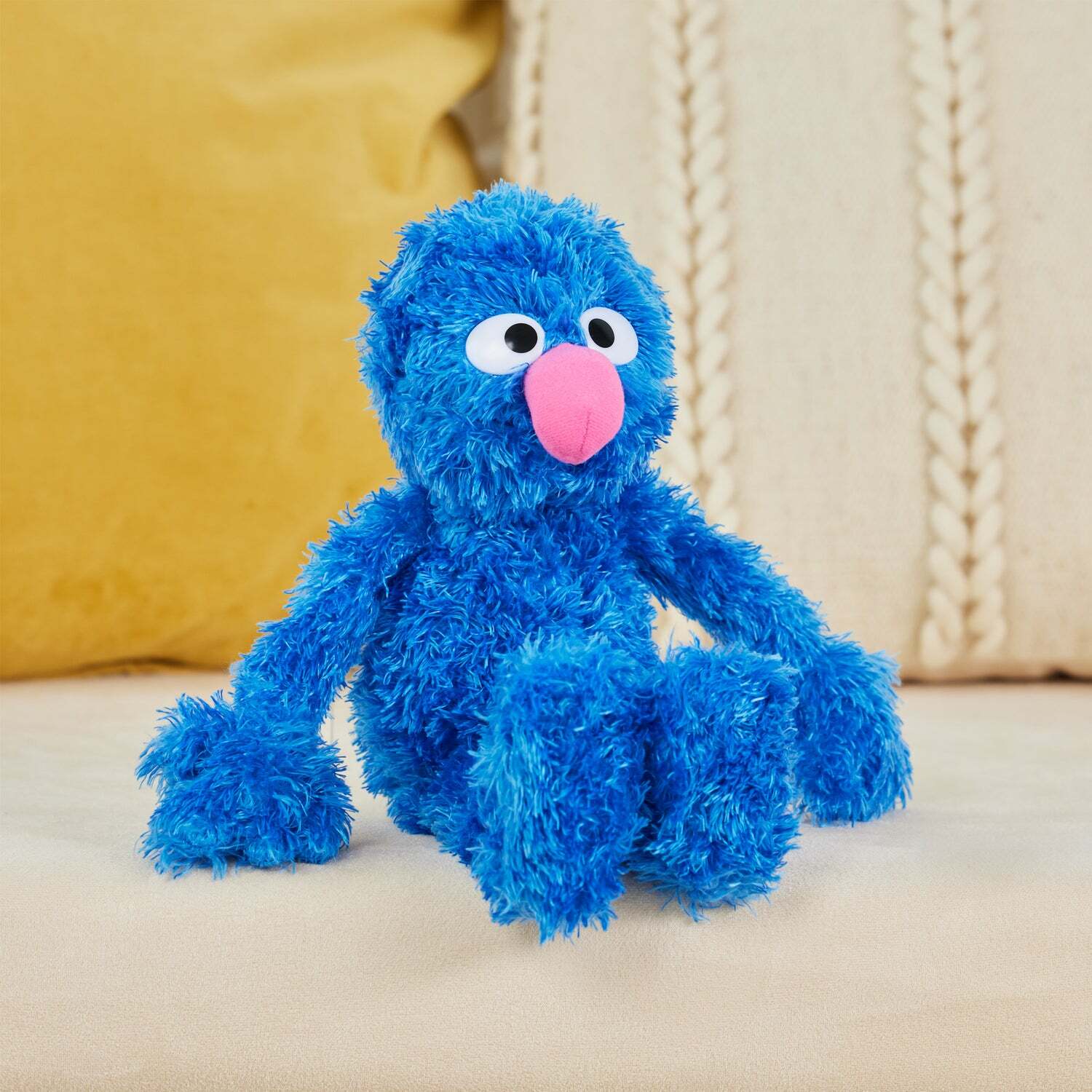 Blue plush toy with a pink nose on a beige surface
