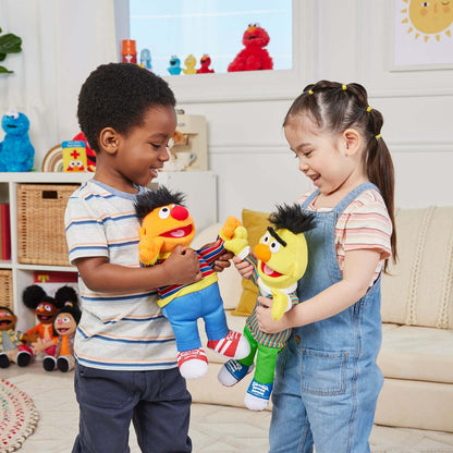 Two children are holding Ernie and Bert  plush, smiling as they play together in a playroom .