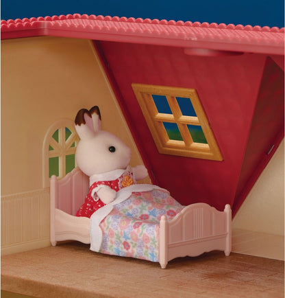 Toy rabbit in a small bed inside a toy house with a red roof.