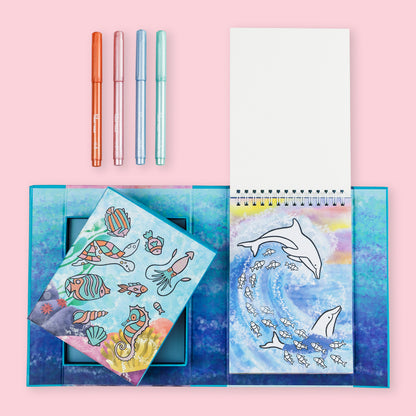 Coloring book with ocean-themed illustrations and markers on a pink background