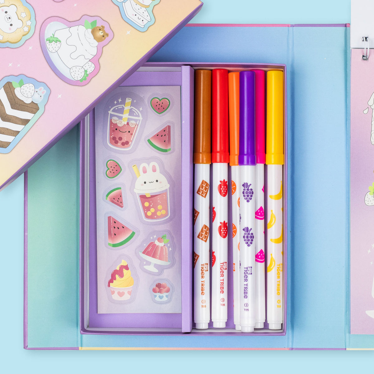 Set of colorful markers and stickers in a pastel box