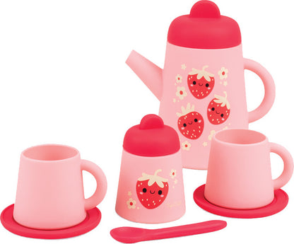 A pink children's tea or coffee set with a teapot, two mugs on saucers, a small container with a lid, and a spoon, all decorated with cute red strawberries and white flowers on a white background.