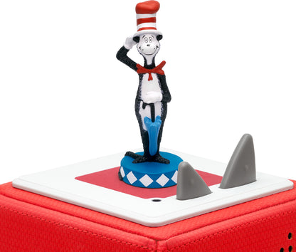 A figurine of the Cat in the Hat from Dr. Seuss books, wearing a red and white hat, standing on a blue and white checkered base. is standing on a red toniebox.