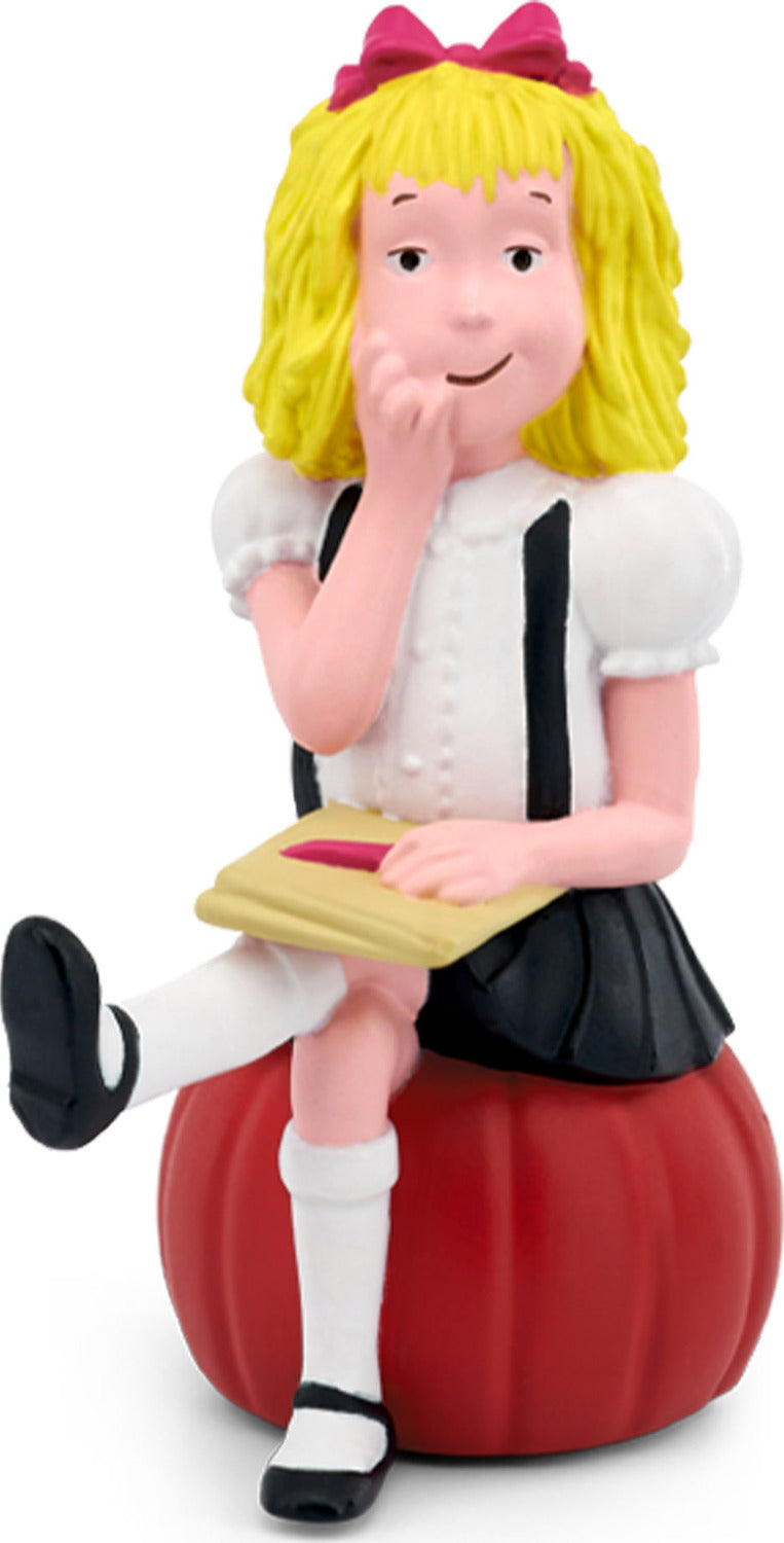 Elois blonde girl wearing a pink hair bow, a white shirt with black suspenders, and a black shirt seated on a red base holding a book.