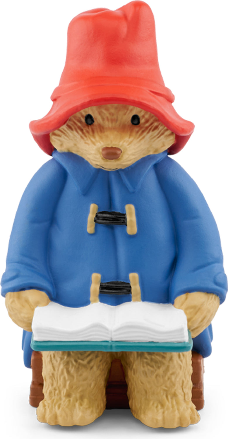 A figurine of Paddington Bear wearing his blue coat and red hat, holding a book.