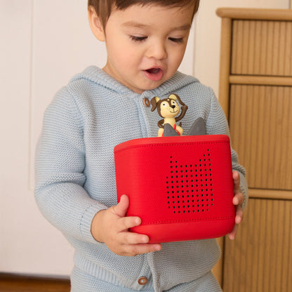 Child holding a red toy with a cartoon character on a light background