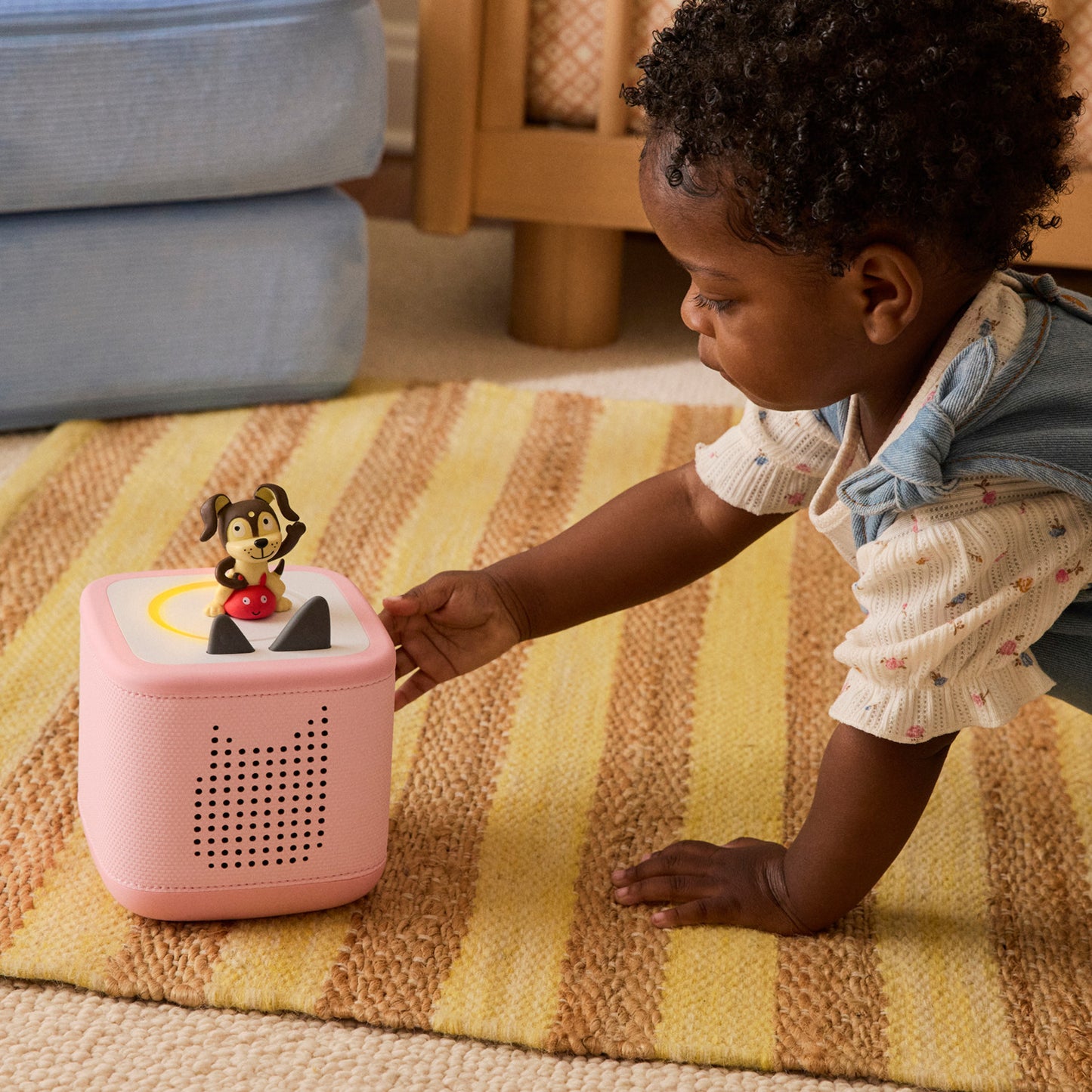 Child playing with a pink toy on a striped rug